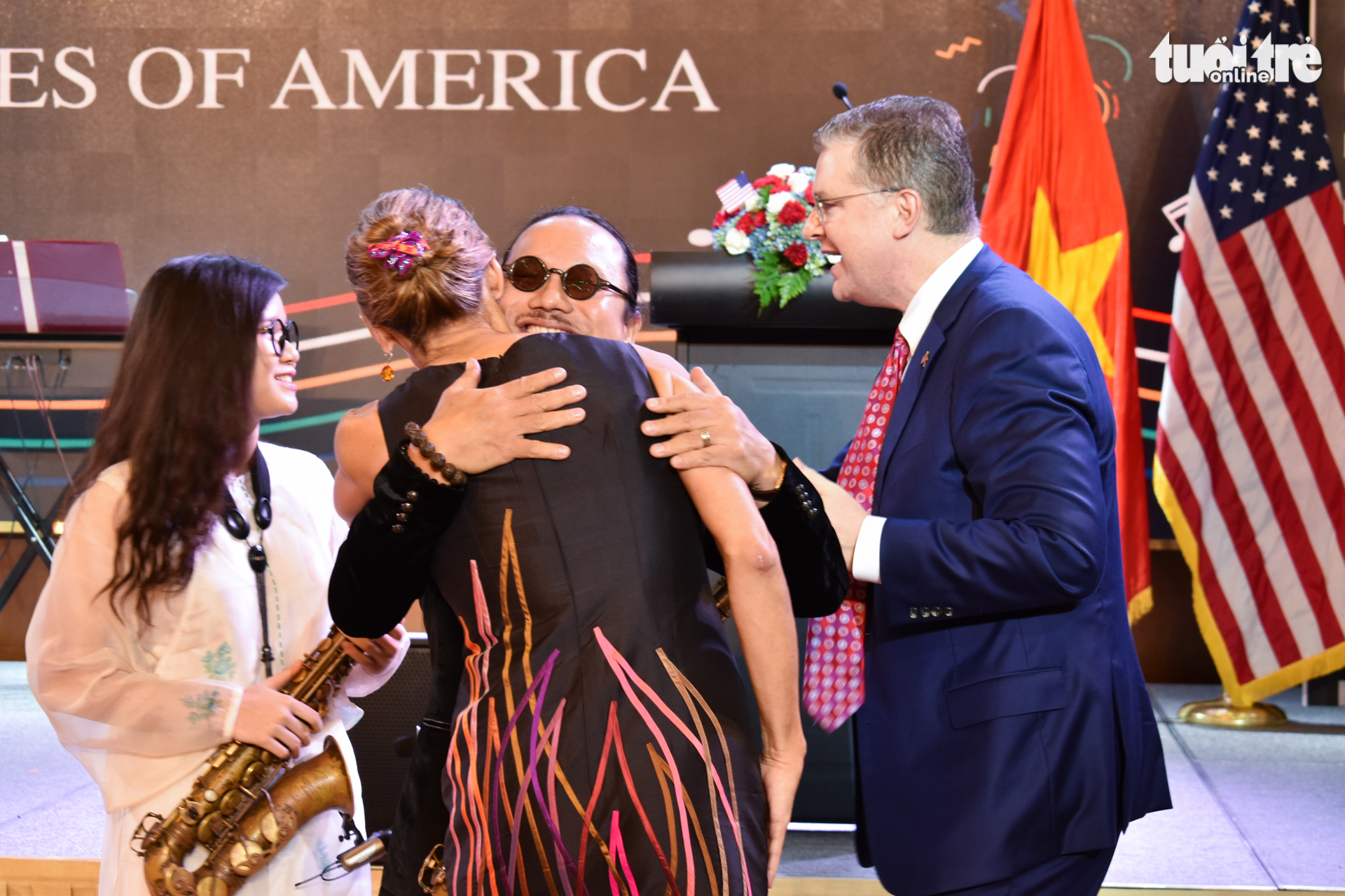 U.S. Consul General in Ho Chi Minh City Mary Tarnowka hugs Vietnamese saxophonist Tran Manh Tuan as U.S. Ambassador to Vietnam Daniel Kritenbrink (R) congratulates Tuan's daughter An Tran after the artists' performance at an event celebrating the 243rd U.S. Independence Day in Ho Chi Minh City on June 5, 2019. Photo: Tuan Son / Tuoi Tre News