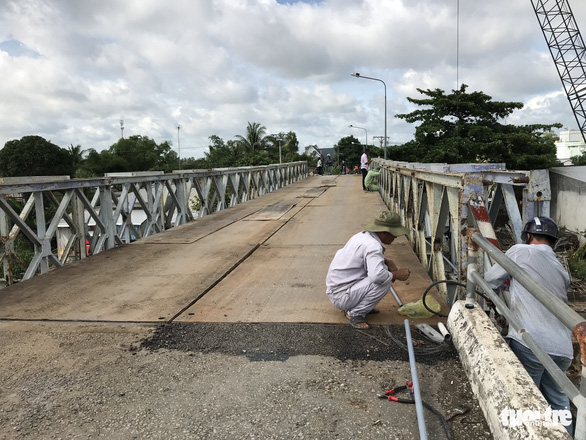 Workers reinstall damaged communications cable lines on the Tan Nghia Bridge in Dong Thap Province, Vietnam on June 7, 2019. Photo: Ngoc Tai / Tuoi Tre