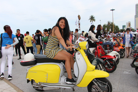 A visitor takes photos with a vintage Vespa scooter in Nha Trang City, Vietnam on June 9, 2019. Photo: Thai Thinh / Tuoi Tre