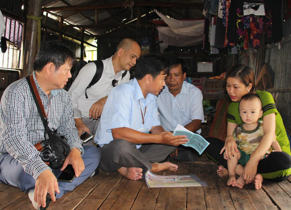 Doctor Nguyen Ngoc Quy (third from left) talks to a family about the importance of vaccinating. Photo: Tan Thai / Tuoi Tre