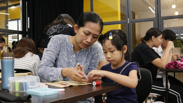 Gia Han (right) works on her wallet with her mother. Photo: Minh Nguyet / Tuoi Tre