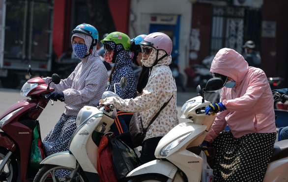 Vietnamese commuters protect themselves from the sun. Photo: Tuoi Tre