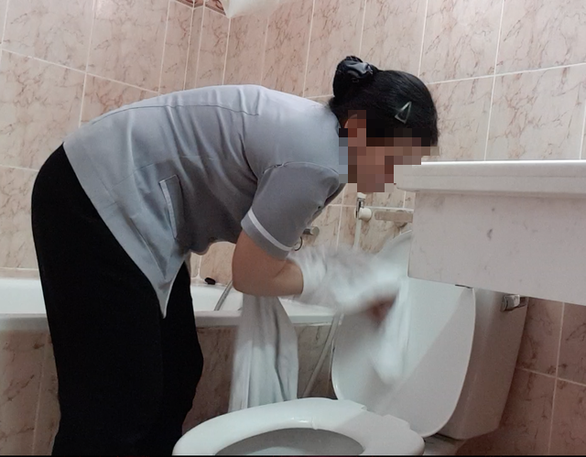 A cleaner cleans a toilet using a towel meant for customer use at a hotel in Ho Chi Minh City. Photo: Tuoi Tre