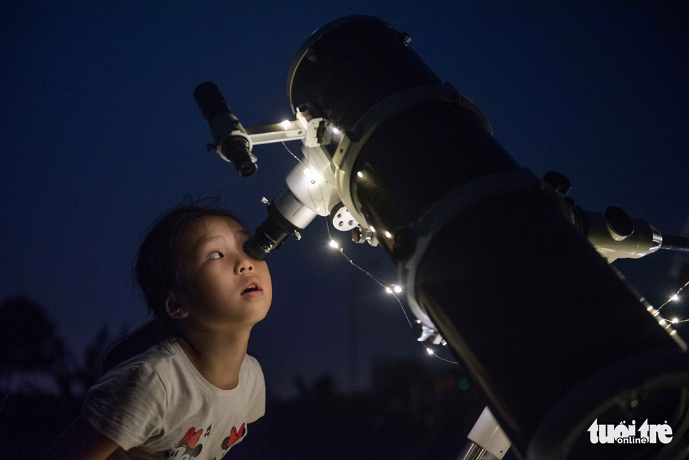 A participant looks through the telescope to watch the eclipse. Photo: Hoang Thanh Tung / Tuoi Tre