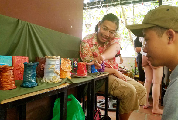 Nguyen Ngoc Thach introduces his upcycled single-use plastic art pieces to a customer. Photo: Ha Thanh / Tuoi Tre