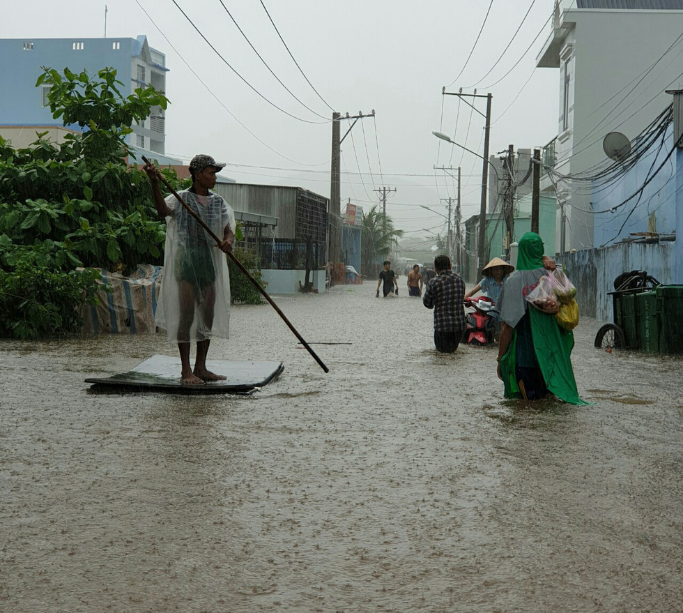 A resident paddles along a flooded road.