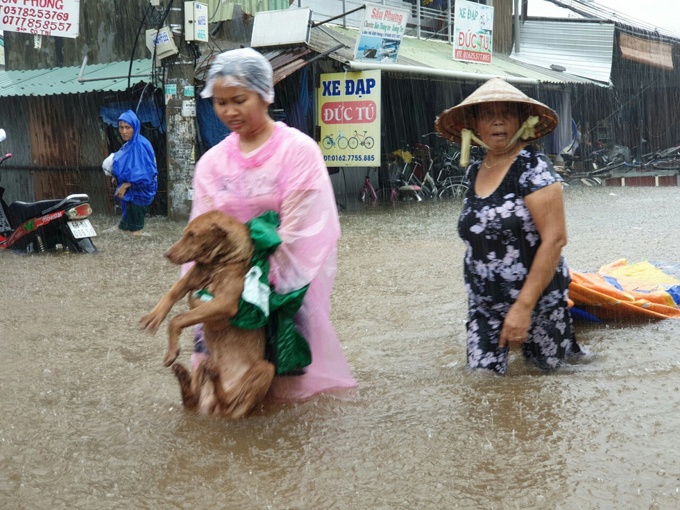 A woman carries her dog as she evacuates from the flooded area.