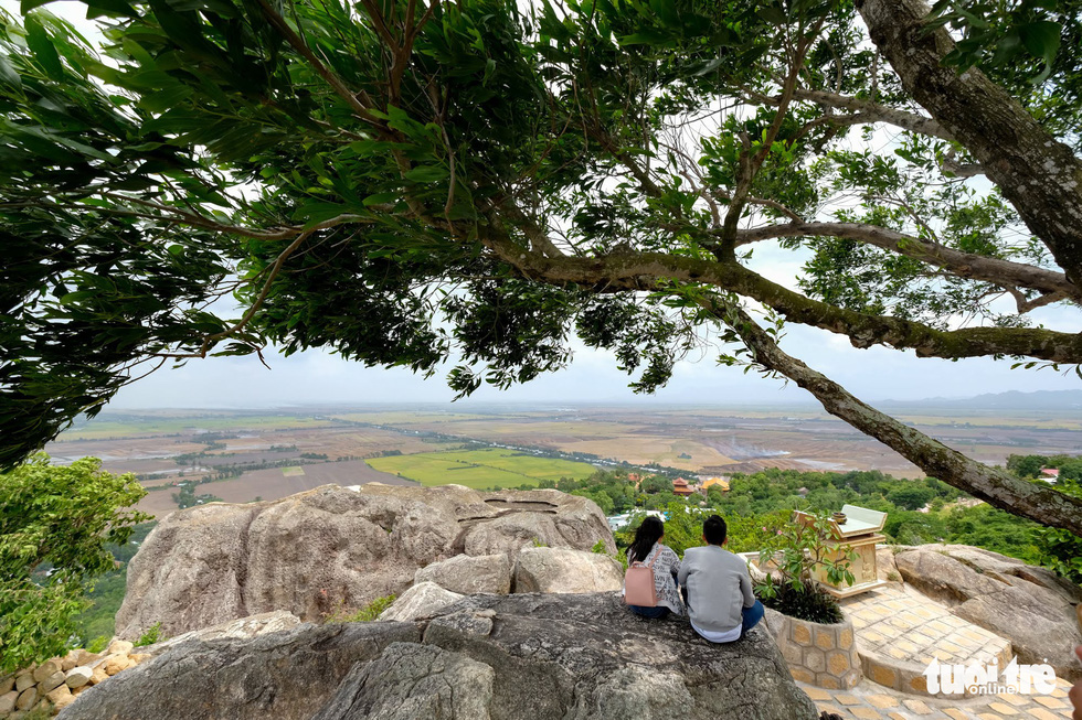 Two visitors look down to admire the landscape surrounding Sam Mountain. Photo: Tuoi Tre