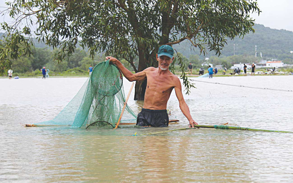 A local resident catches fish along an inundated street.