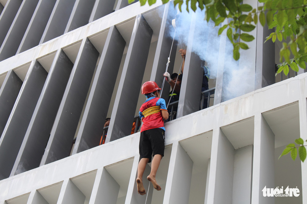 A child practices exit from a building by using rescue rope during a firefighting training. Photo: Le Van Quang / Tuoi Tre