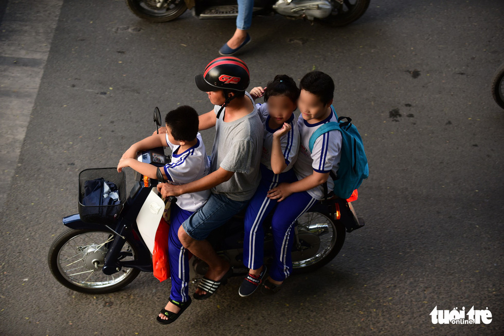 A man carries four children, who wear no helmet, on one vehicle in Ho Chi Minh City. Photo: Quang Dinh / Tuoi Tre