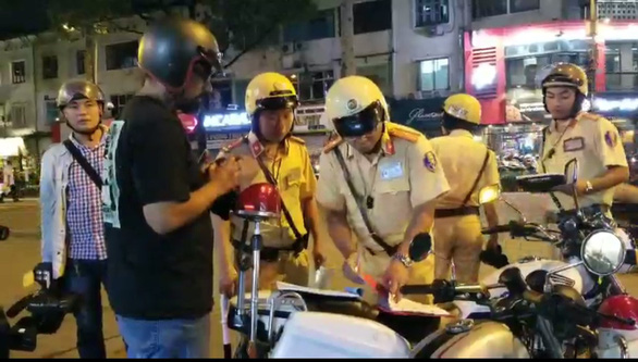A foreigner is pulled over by traffic police officers in Ho Chi Minh City for a violation in this still photo taken from a footage.