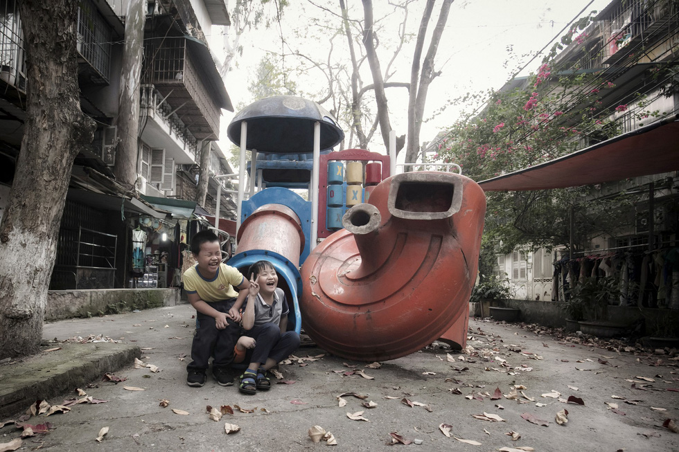 Two children smile in absolute happiness while playing with sliders in the old playground in Hanoi. Photo: Hoang Anh Tuan