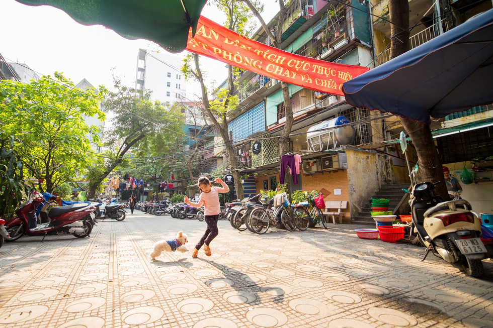 A girl plays with her dog inside an old residential area in Hanoi. Photo: Pham Quoc Trung