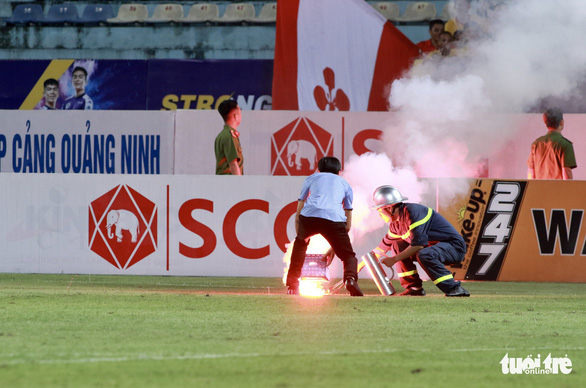 A firefighter and a man try to put out a burning flare at Hang Day Stadium in Hanoi, September 11, 2019. Photo: Tuoi Tre