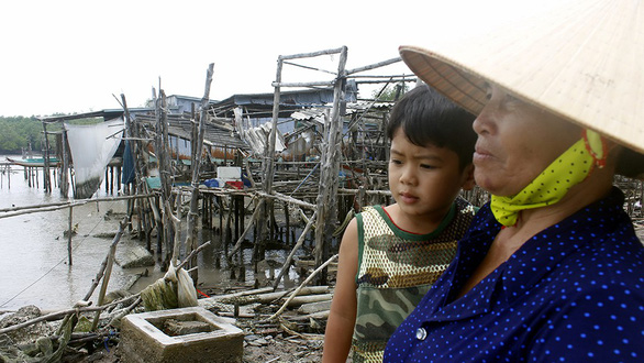 A resident in Dat Mui Commune looks at her home before relocating to another area. Photo: Tien Trinh / Tuoi Tre