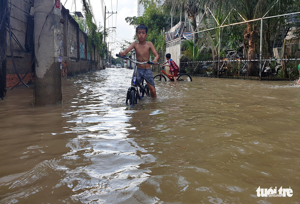 Children cycle on a flooded street in District 2. Photo: Minh Hoa / Tuoi Tre