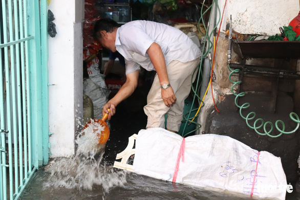 A man scoops water out of his home in District 4. Photo: Xuan Mai / Tuoi Tre