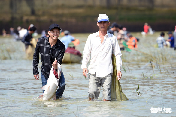 A man smiles as he carries a freshly caught fish near the Tri An hydropower dam in Dong Nai Province, Vietnam on September 30, 2019. Photo: A Loc / Tuoi Tre