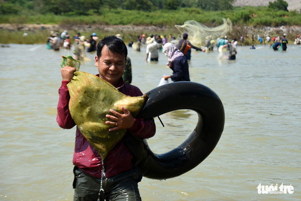 A man carries freshly caught fish in a bag near the Tri An hydropower dam in Dong Nai Province, Vietnam on September 30, 2019. Photo: A Loc / Tuoi Tre
