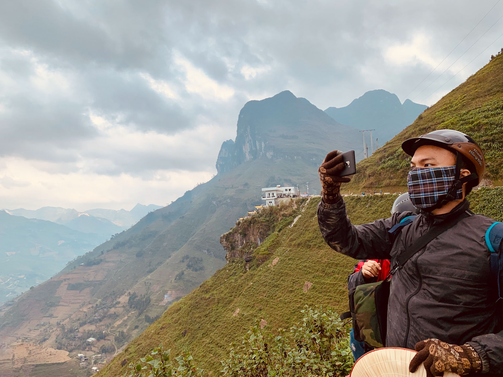 A traveler takes photos of the Ma Pi Leng mountain pass in Ha Giang Province, Vietnam with the 'Ma Pi Leng Panorama building spotted in the background. Photo: Tran Phuong / Tuoi Tre