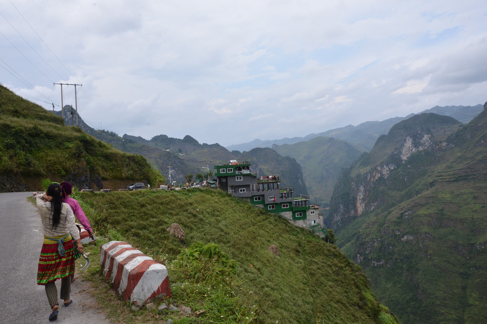 Two women walk on Ma Pi Leng mountain pass in Ha Giang Province, Vietnam, with the Ma Pi Leng Panorama building spotted afar. Photo: Vu Tuan / Tuoi Tre
