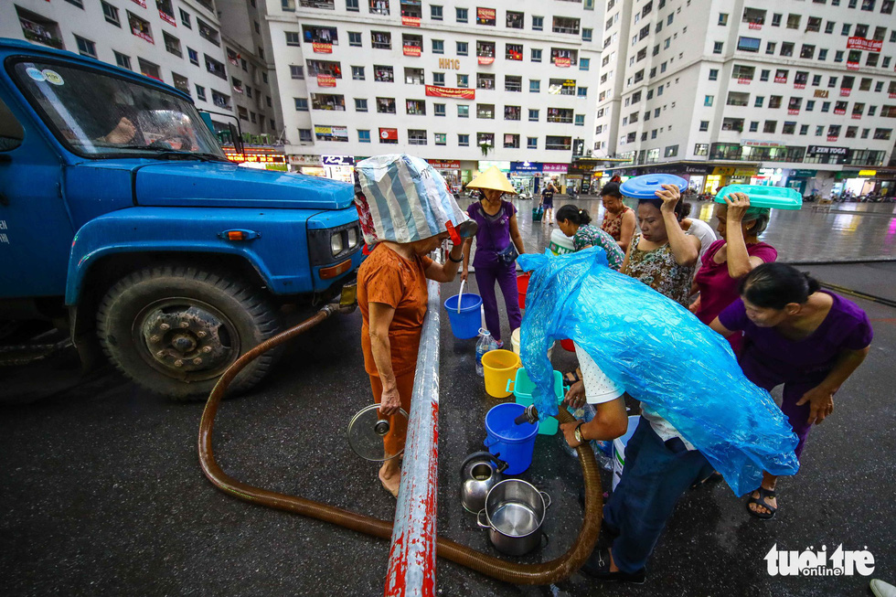 People queue for clean water in the rain in Hanoi. Photo: Nguyen Khanh / Tuoi Tre