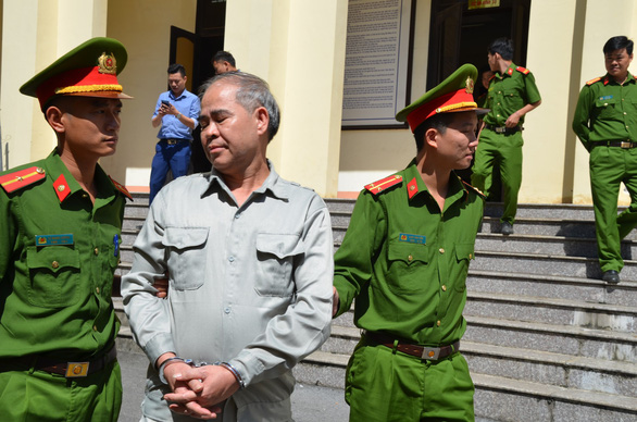 Dinh Bang My, 58, is escorted out of the courtroom by two policemen in Phu Tho Province, located in northern Vietnam, October 29, 2019. Photo: Giang Long / Tuoi Tre