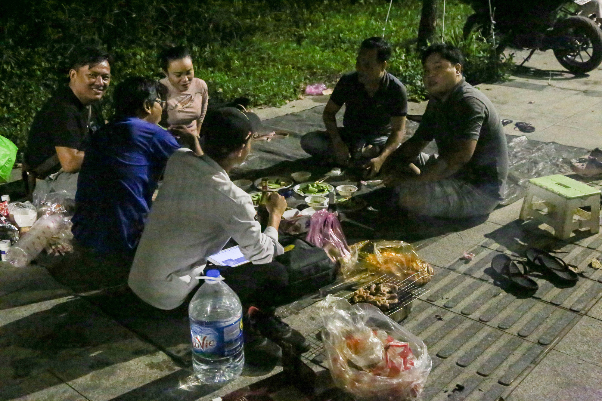 A group of young people throw a BBQ party on the sidewalk in the Thu Thiem New Urban Area. Photo: Thao Le / Tuoi Tre