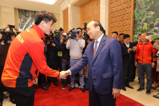 Vietnam's Prime Minister Nguyen Xuan Phuc (R) and the U22 men's football team member Tan Sinh shake hands at the Government Office in Hanoi on December 11, 2019. Photo: Viet Dung / Tuoi Tre