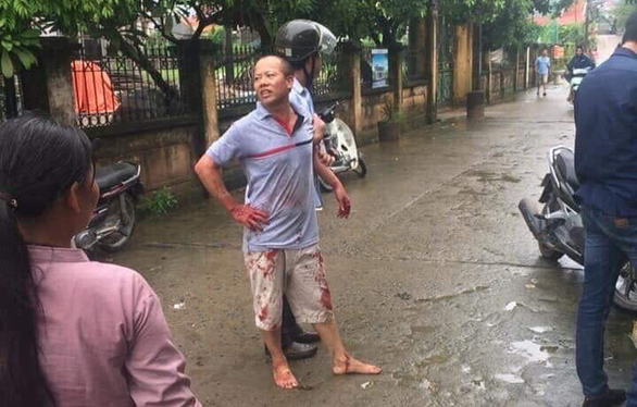 Nguyen Van Dong is seen being held by an officer after killing four members of his brother's family in Hanoi on September 1, 2019. Photo: Tuoi Tre