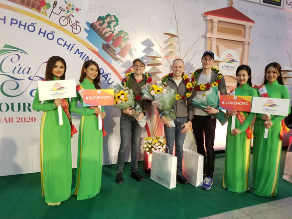 The first visitors from abroad receive flowers and wishes from Ho Chi Minh City tourism officials at Tan Son Nhat International Airport, January 1, 2020. Photo: Gia Khang / Tuoi Tre