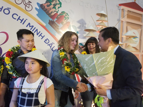 Bui Ta Hoang Vu (R), director of the Ho Chi Minh City Department of Tourism, gives flowers to new visitors touching down at Tan Son Nhat International Airport from France, January 1, 2020. Photo: Gia Khang / Tuoi Tre