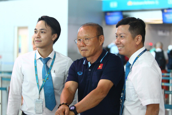 Two airport employees pose for a photo with Vietnam’s head coach Park Hang Seo (C) at Tan Son Nhat International Airport on the afternoon of January 1, 2020. Photo: N.K. / Tuoi Tre