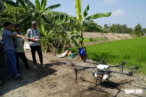Lam Trong Nghia (R) demonstrates how to operate a crop dusting drone. Photo: Ngoc Tai / Tuoi Tre