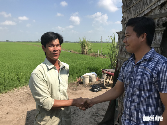 Le Quoc Trung (R) shakes hands with a farmer after sealing a deal to supply drones for crop dusting. Photo: Ngoc Tai / Tuoi Tre