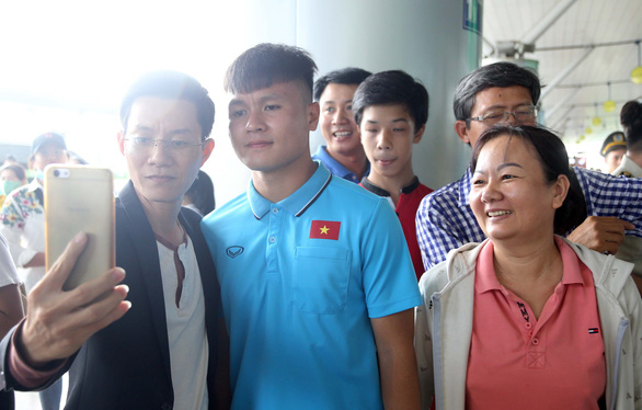Two people pose for a photo with Vietnam’s midfielder Nguyen Quang Hai (C) at Tan Son Nhat International Airport on the afternoon of January 1, 2020. Photo: N.K. / Tuoi Tre