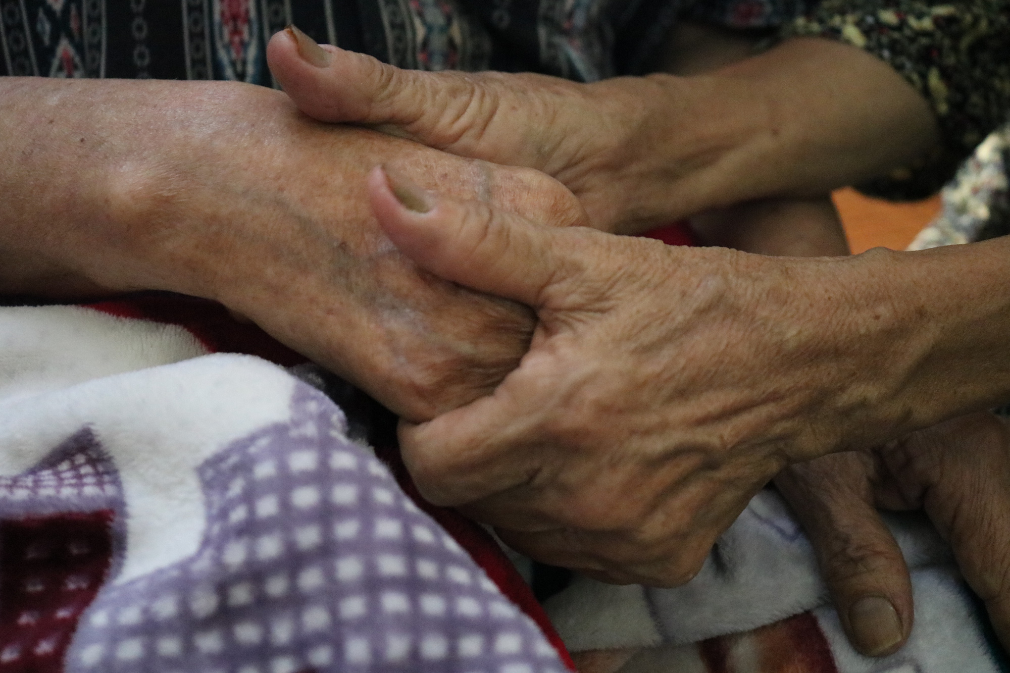 As the wrinkled hands hold each other, she hopes her husband will be in good health so they can enjoy another Tet holiday together. Photo: Ngoc Phuong / Tuoi Tre
