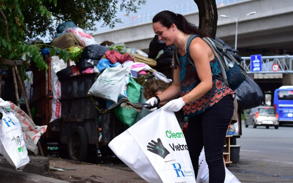 A young woman collects trash at the campus of Vietnam National University-Ho Chi Minh City in Thu Duc District, Ho Chi Minh City. Photo: Trieu Van / Tuoi Tre