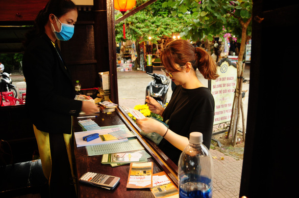 An attendant wears mask while interacting with a customer at a ticket booth in Hoi An Ancient Town, located in the central province of Quang Nam. Photo: B.D / Tuoi Tre