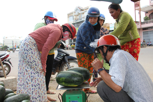 Customers buy watermelons on sale by the sidewalk of a street in the south-central province of Binh Dinh. Photo: Thai Thinh / Tuoi Tre