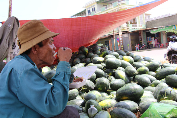 A farmer sits by a pile of watermelons from his harvest in the south-central province of Binh Dinh. Photo: Thai Thinh / Tuoi Tre