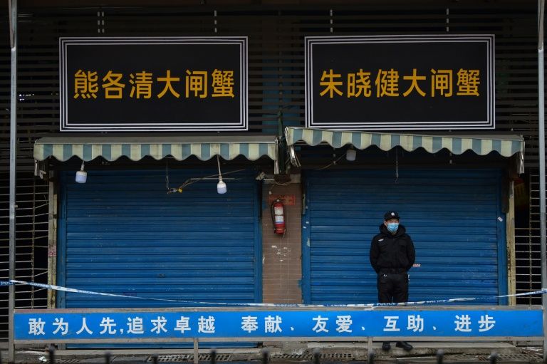 A man stands guard a locked down seafood market in the central Chinese province of Hubei. Photo: AFP