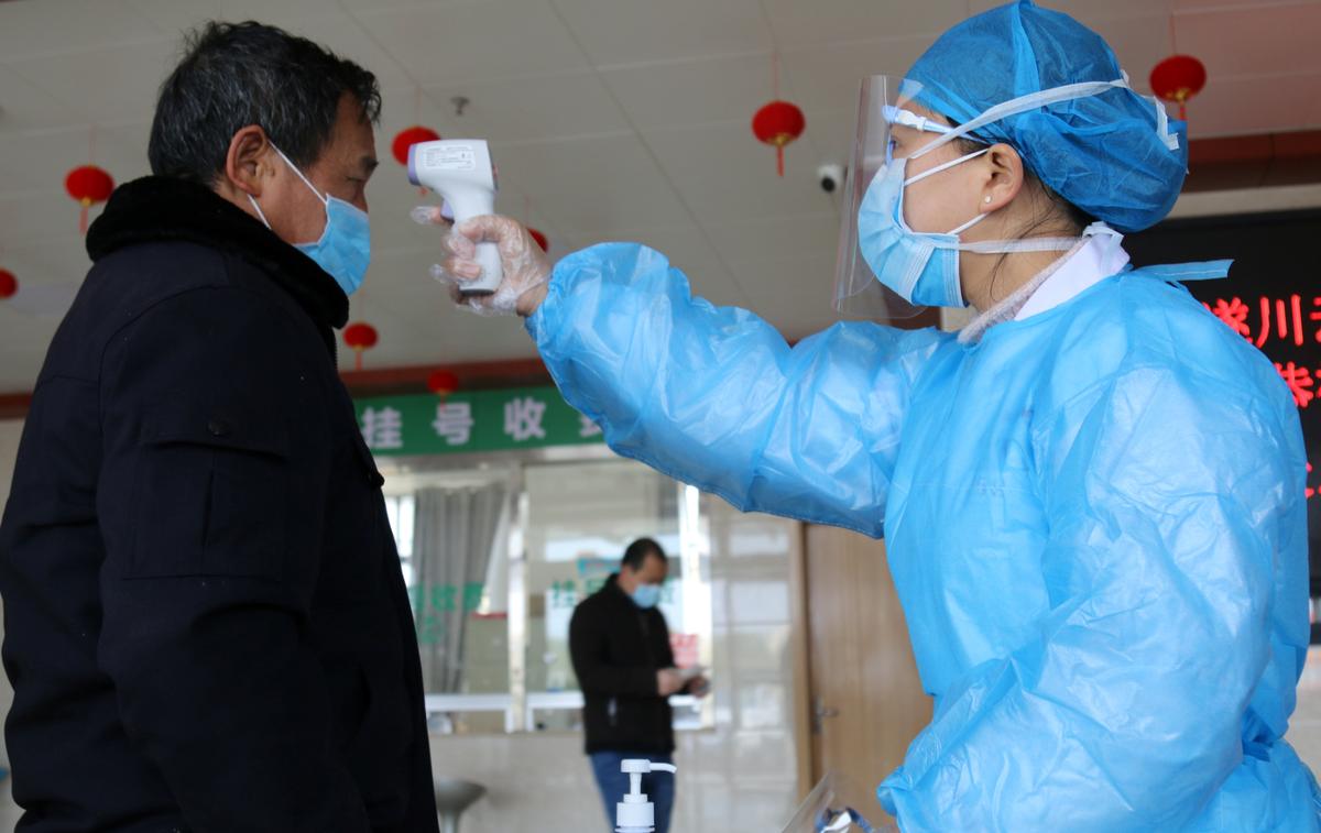 FILE PHOTO: A medical worker takes body temperature measurement of a man at an entrance to a hospital as the country is hit by an outbreak of the new coronavirus, in Suichuan, Jiangxi province, China February 2, 2020. China Daily via REUTERS