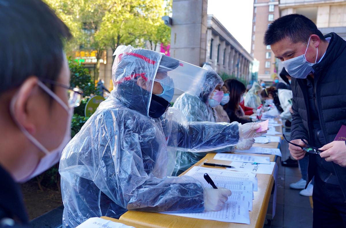 FILE PHOTO: Community workers wearing makeshift protective suits help residents to register for coupons to purchase face masks at pharmacies, in Shanghai, China as the country is hit by an outbreak of the new coronavirus, February 2, 2020. China Daily via REUTERS