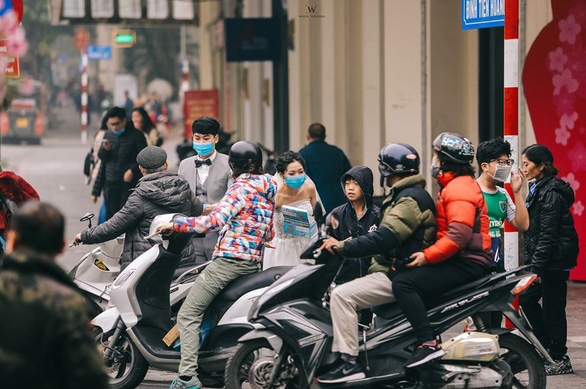A couple gives away medical masks to commuters and passers-by on a street in Hanoi for their pre-wedding photos in this picture uploaded on Facebook