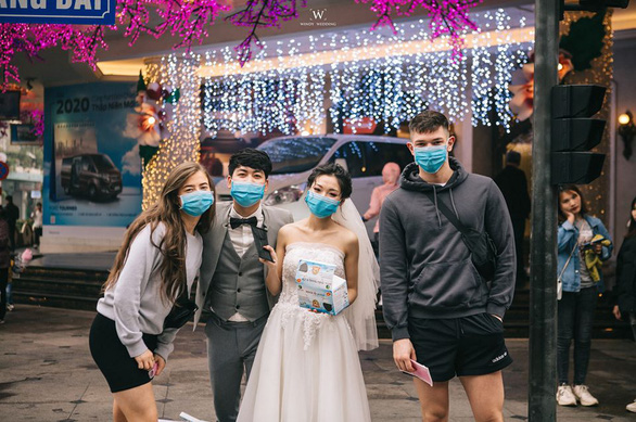 A couple gives away medical masks to commuters and passers-by on a street in Hanoi for their pre-wedding photos in this picture uploaded on Facebook