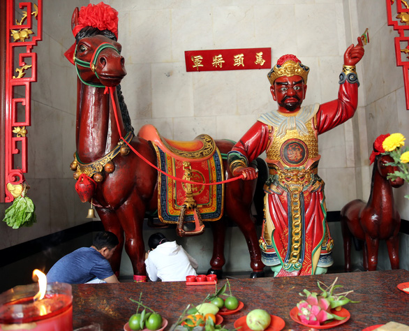 A man and a woman crawl under a horse statue to perform a ritual at the First Full Moon Festival, or Tet Nguyen Tieu at Nghia An Pagoda in District 5, Ho Chi Minh City