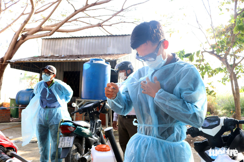 A staff member puts on a protective suit before spraying disinfectant at a venue in the southernmost Vietnamese province of Ca Mau. Photo: Khanh Tran / Tuoi Tre