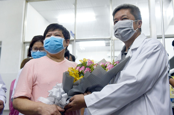 Li Ding (L) receives a bouquet from a doctor upon his discharge from Cho Ray Hospital in Ho Chi Minh City, Vietnam, February 12, 2020. Photo: Duyen Phan / Tuoi Tre